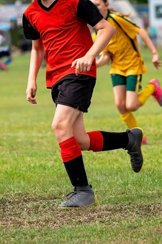 An action of shot of young boys playing rugby. One boy is leaning into a tackle with the ball tucked under his arm.