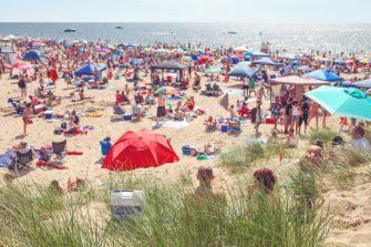 A beach crowded with colourful umbrellas and lots of people