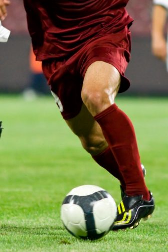 Soccer players legs as they run for the ball.