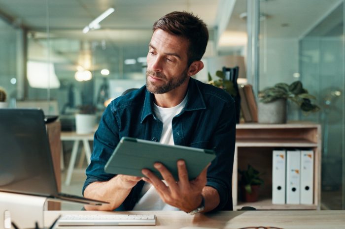 Tablet, reading and laptop with business man in office for planning, ui designer and app review. Developer solutions, client feedback and research with person in agency for project idea and startup.