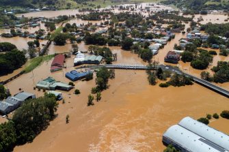 Brown floodwaters fill the streets of Lismore, submerging cars and flooding businesses