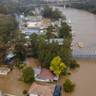 Houses beside the Georges River are engulfed by brown flood water