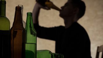 Silhouette of man drinking from a beer bottle