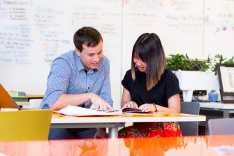 Photograph of a conversation between two adults discussing the disability inclusion plan