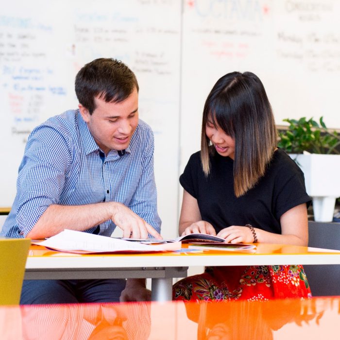 Photograph of a conversation between two adults discussing the disability inclusion plan