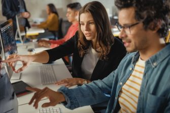 Diverse Multiethnic Group of Female and Male Students Sitting in College Room, Collaborating on School Projects on a Computer. Young Scholars Study, Talk, Apply Academic Skills and Knowledge in Class.