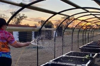 Two people helping with watering the community garden and installing the wicked beds.