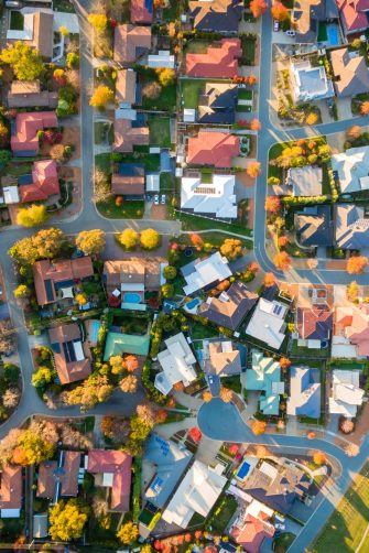An aerial photograph showcasing a residential neighborhood in Australia, highlighted by vibrant autumn foliage and a variety of homes.