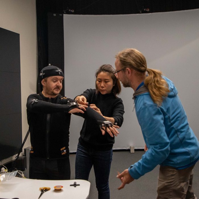 A group of people fitting a green screen suit in the 3DX Lab at UNSW Paddington Campus