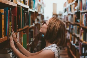 Woman looking at books on a library shelf