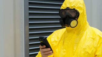 Picture of worker in protective chemical suit checking radiation with geiger counter