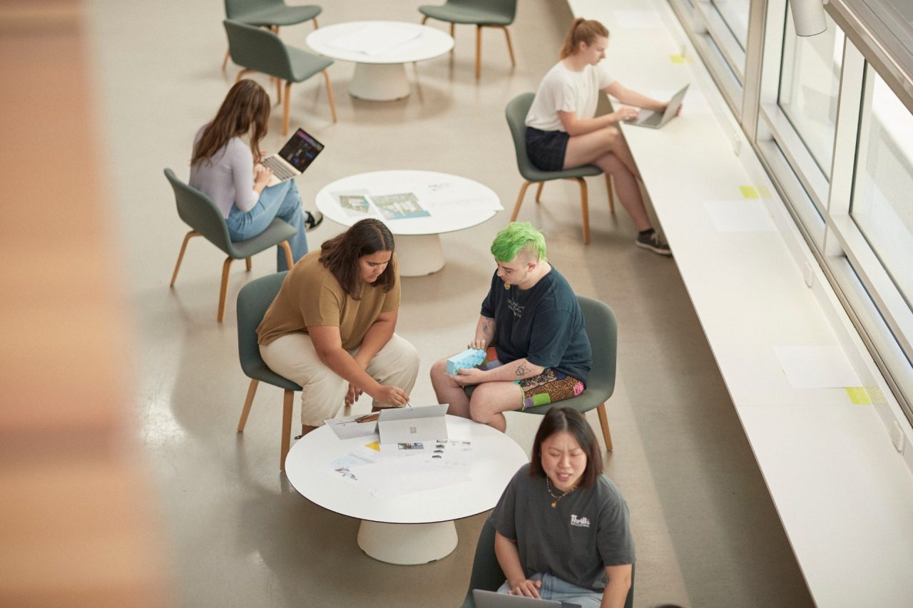 Art and design students discussing work inside the Red Center build enviroment study space.