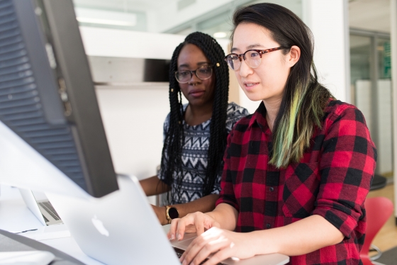 two woman wearing glasses working with laptop