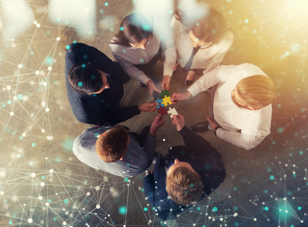 Business people join puzzle pieces in office. Concept of teamwork and partnership. double exposure with internet network effects