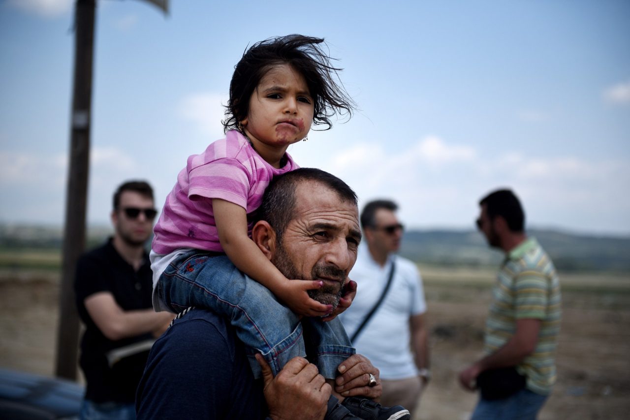Idomeni, Greece - May 26, 2016. A Syrian man carries his daughter, as refugees abandon the makeshift camp of Idomeni in northern Greece, after the evacuation operation by the Greek police.
