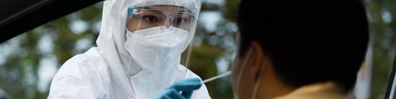 Health professional in PPE suit  giving nasal swab to person in car for   coronavirus(covid-19) PCR test 