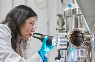 A woman in a lab coat looking at solar cell technology.