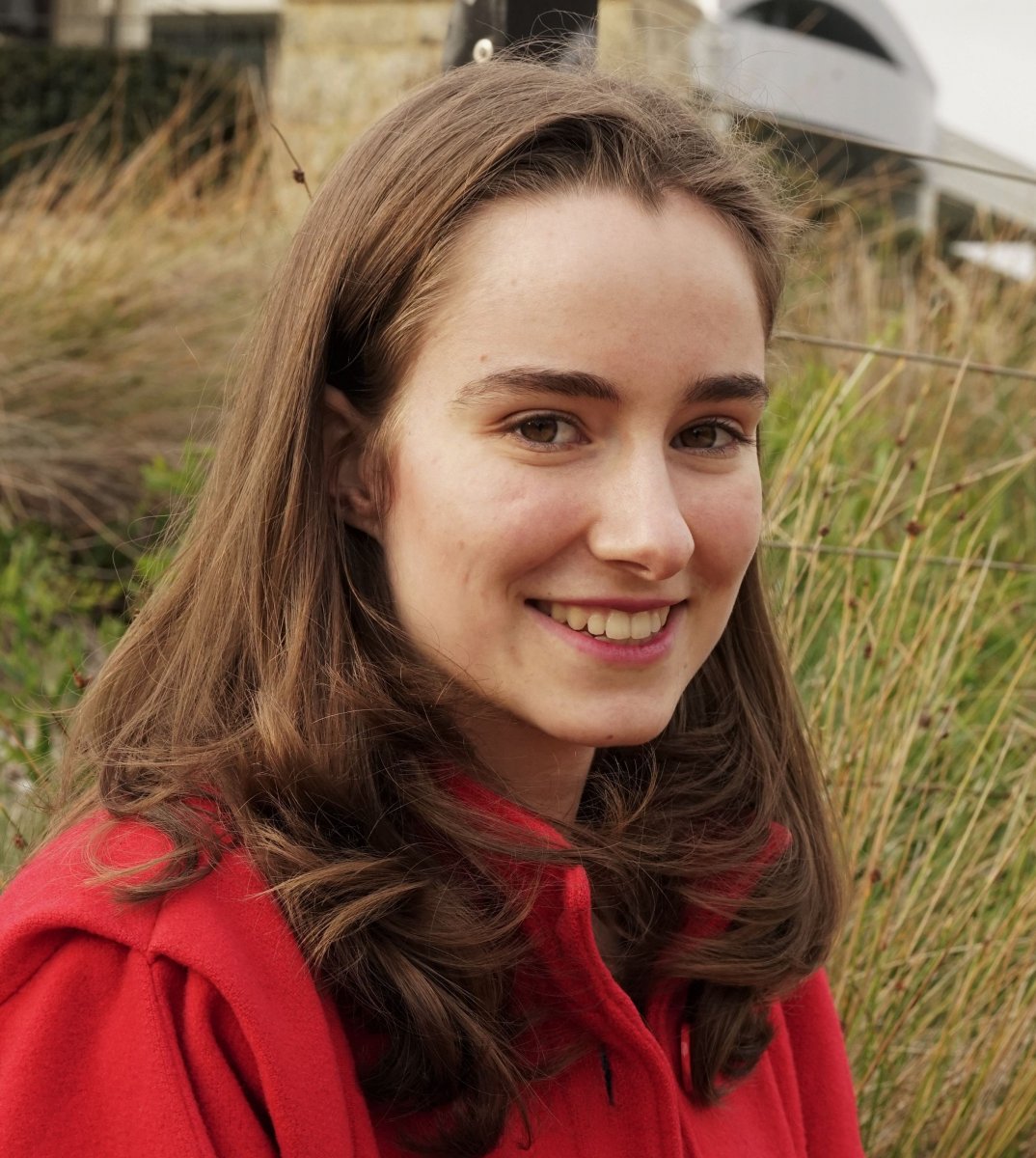 Jess Boyle - Young woman in red coat smiling at camera